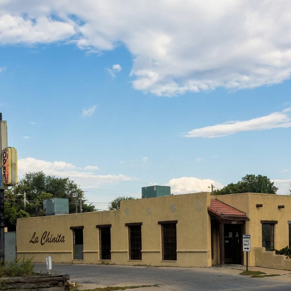La Chinita Mexican restaurant building with tan stucco walls, roadside sign, landscaped entrance, and blue sky.