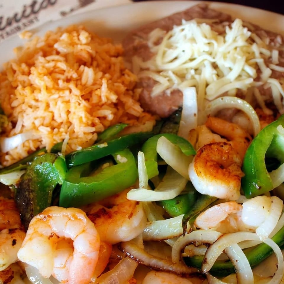 Mexican platter with grilled shrimp, peppers, onions, guacamole, rice, refried beans, shredded cheese, and pico de gallo.